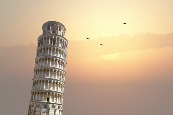 Sunset over the Leaning Tower of Pisa with three birds flying above.