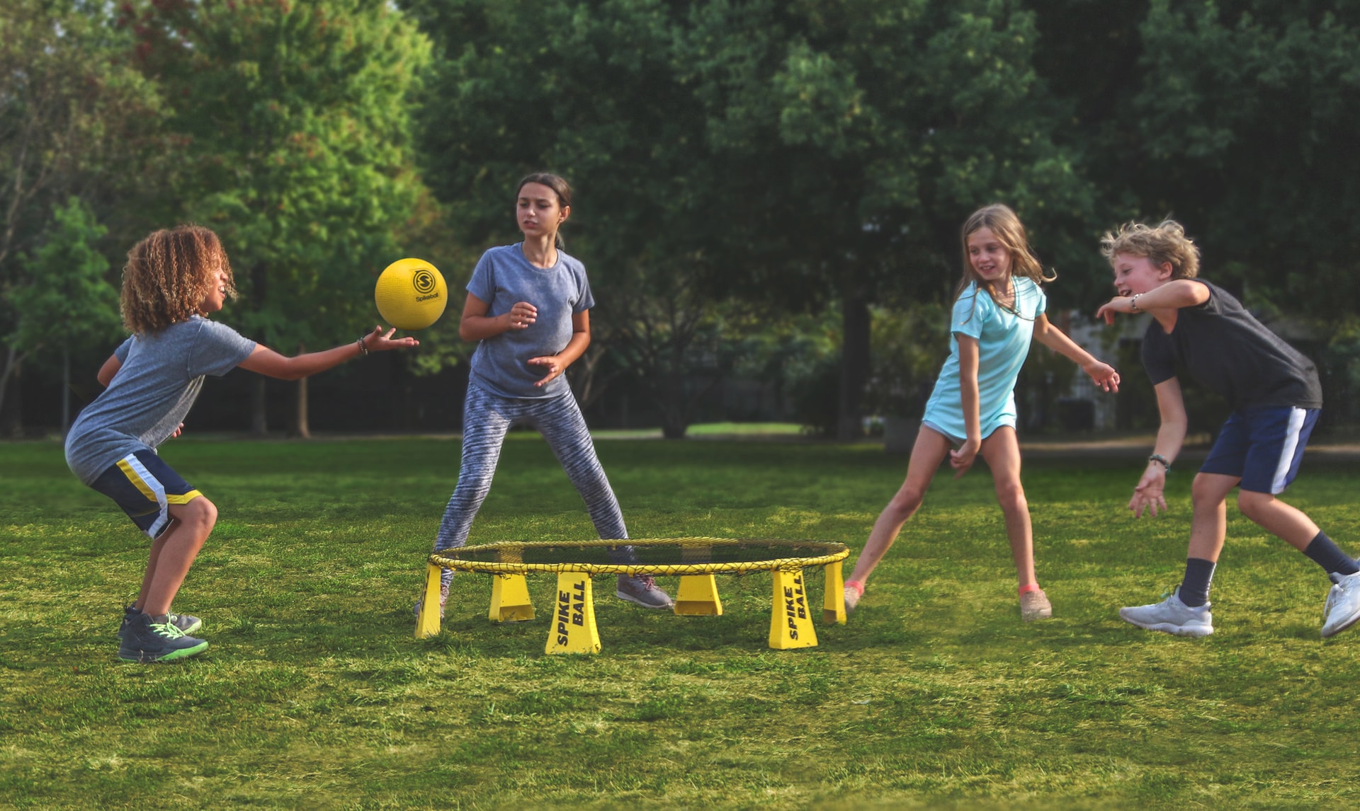A group of kids plays spikeball outside at a playdate.