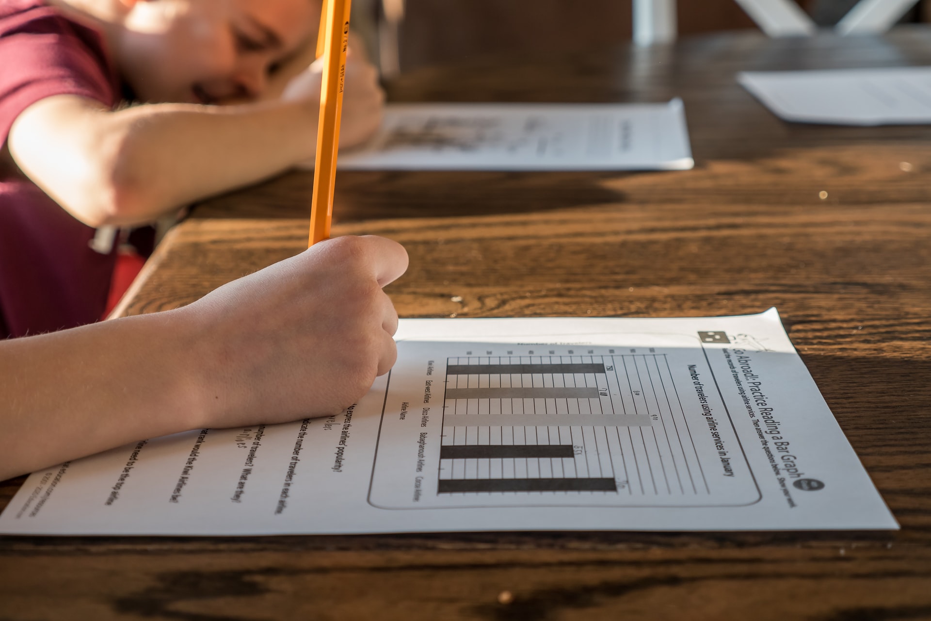 Two children complete math worksheets.