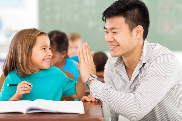 A teacher high-fives a student who