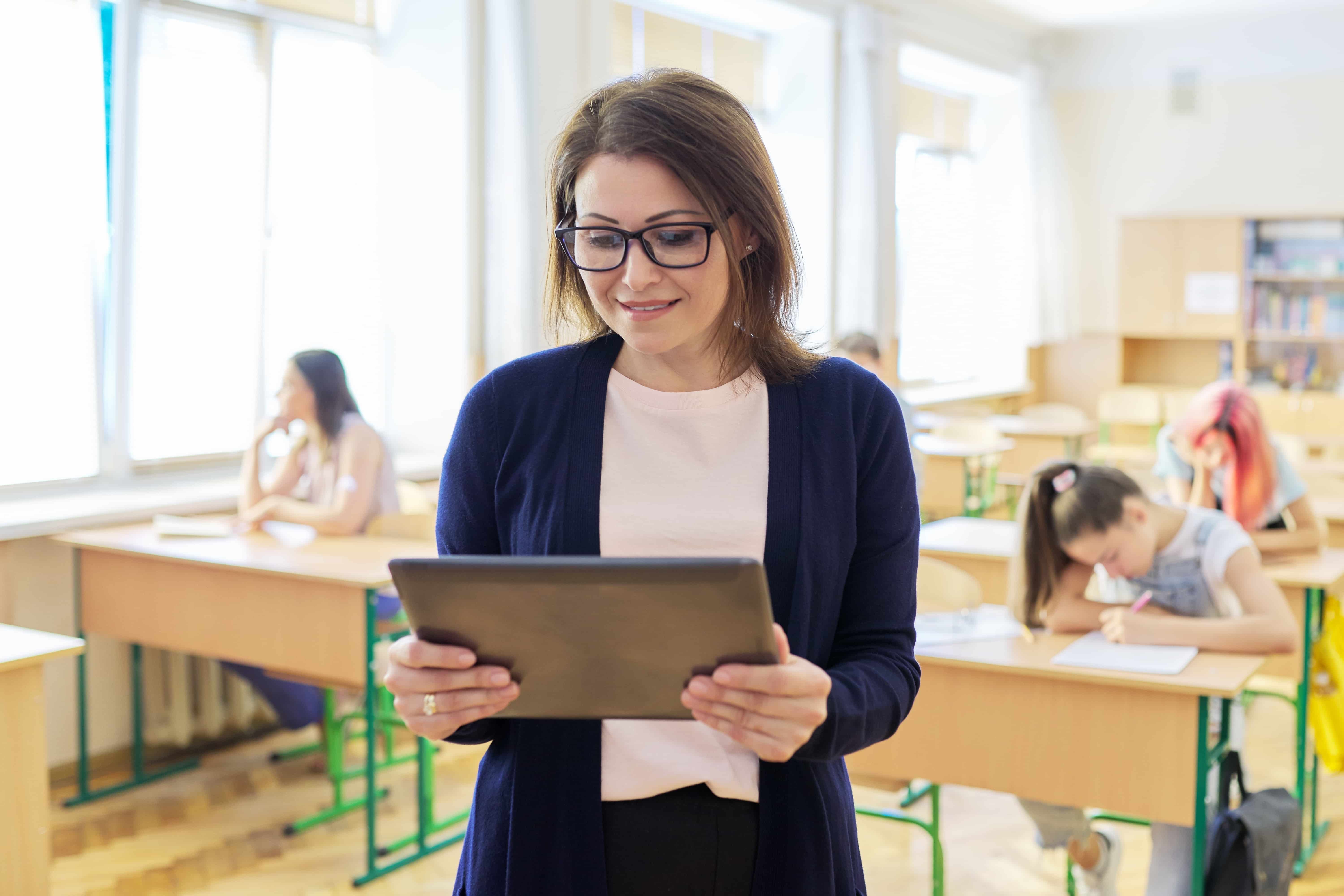 Teacher reading her exit ticket responses on tablet in class.